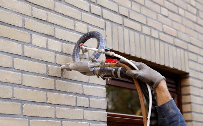 Monteur vult een spouwmuur met isolatiemateriaal